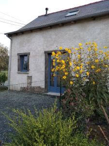 une maison avec une porte bleue et des fleurs jaunes dans l'établissement Studio de charme à la campagne, à Clayes