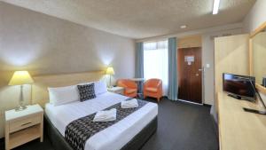 a hotel room with a bed and a flat screen tv at Goulburn Central Motel in Goulburn