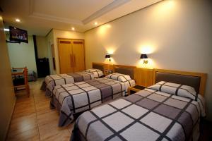 um quarto de hotel com três camas e uma televisão em Hotel Columbia em São Paulo