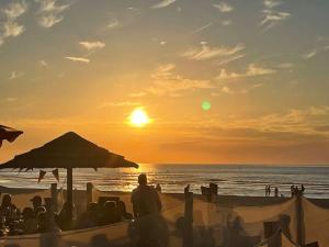 - un groupe de personnes assises sur la plage pour admirer le coucher du soleil dans l'établissement Dam&HelMalo - 150m de la plus belle plage du Nord., à Dunkerque