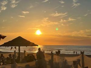a group of people sitting on the beach watching the sunset at Dam&HelMalo - 150m de la plus belle plage du Nord. in Dunkerque
