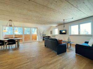 a living room with a wooden ceiling and a table and chairs at Haus Wiesenquelle, Deluxe-Apartment 'Feld & Berg' in Feldberg
