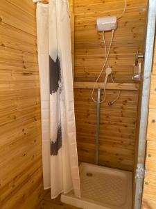 y baño de madera con ducha y cortina de ducha. en נירוונה במדבר en Be'er Milka
