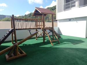 un parque infantil de madera al lado de una casa en PUERTO VENTURA Flat Beira Mar de Cabo Branco, en João Pessoa