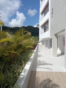 una acera vacía junto a un edificio blanco con palmeras en PUERTO VENTURA Flat Beira Mar de Cabo Branco, en João Pessoa