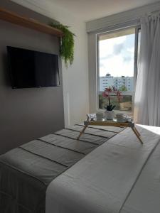 Un dormitorio con una cama grande y una mesa. en PUERTO VENTURA Flat Beira Mar de Cabo Branco, en João Pessoa
