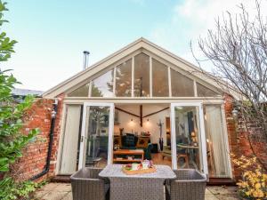 een glazen huis met een tafel en stoelen bij The Bothy at Snape Hall in Snape