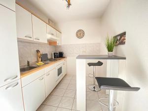 cocina con armarios blancos y taburete en Wohlfühl-Apartment mit kostenfreier Tiefgarage, WiFi und Kaffee, en Leipzig