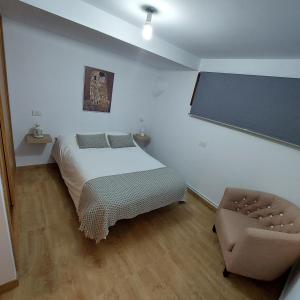 1 dormitorio con cama, silla y pantalla en Casa Da Devesa, en Nigrán
