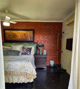 1 dormitorio con cama y pared de ladrillo en Ladybird, en Durban