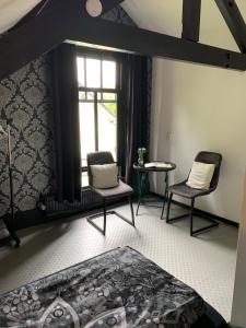 - une chambre avec deux chaises, un lit et une fenêtre dans l'établissement overnachten in Zeeland, à Burgh-Haamstede