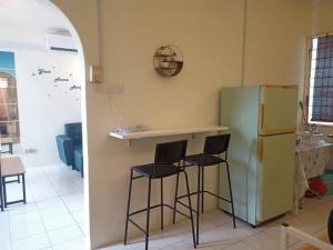 a kitchen with two bar stools and a refrigerator at Fuji Home in Bayan Lepas