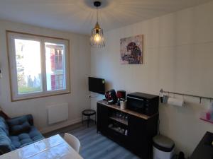 uma sala de estar com um sofá azul e uma janela em appartement 2/3 personnes em La Bourboule