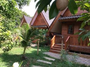 een houten huis met een trap ervoor bij Himawari Restaurant & Cottage in Ban Nong Hin