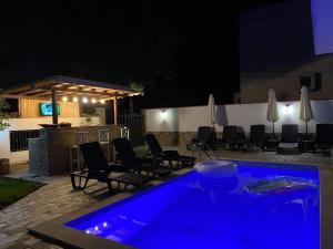 una piscina con illuminazione blu in un cortile posteriore di notte di Апартамент "Вила Аква" a Burgas