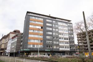 un gran edificio gris con gente parada frente a él en Modernes und Zentralgelegenes Apartment mit Küche, Netflix, und Balkon, en Duisburg