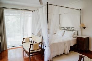 a bedroom with a canopy bed and a chair at A Luxury Seafront Villa with amazing ambience and view in Alyfantá