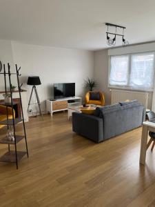 a living room with a gray couch and a tv at Dam&HelMalo - 150m de la plus belle plage du Nord. in Dunkerque