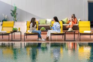 un grupo de mujeres sentadas en sillas junto a una piscina en ibis Jeddah City Center en Yeda