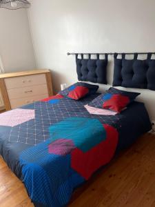 - un lit bleu avec des couvertures et des oreillers colorés dans l'établissement Dam&HelMalo - 150m de la plus belle plage du Nord., à Dunkerque