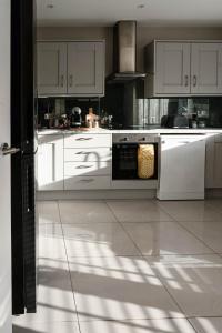 a kitchen with white cabinets and white appliances at Glen Burren House in Newcastle