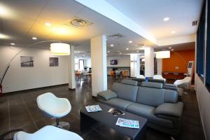 a living room with a couch and a table and chairs at All Suites Appart Hôtel Aéroport Paris Orly – Rungis in Rungis