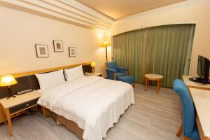 um quarto de hotel com uma cama e uma televisão em Ardi Hotel em Yuanlin