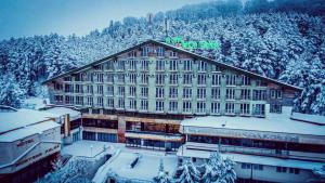 a large building with snow on it in front of a mountain at Hotel Montana Palace in Kruševo