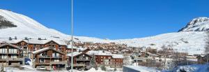 een stad in de sneeuw met een berg op de achtergrond bij Le Val d'Huez, Vue sur le Village et le Domaine in Huez