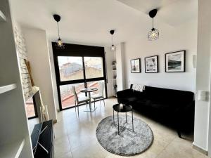 uma sala de estar com um sofá preto e uma mesa em Acogedor apartamento entero em Terrassa