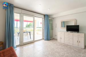 a living room with a television and sliding glass doors at Residencial Casablanca Casa Azahar in Alcossebre