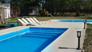 una piscina con tumbonas y una piscina en Cabañas La Deseada (Ranchos, Buenos Aires) en Ranchos
