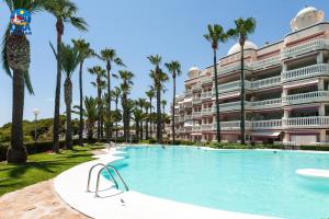 una piscina frente a un gran edificio con palmeras en Residencial Casablanca Casa Azahar, en Alcossebre