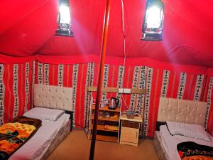 a room with a red tent with two beds at Almazham camp resort in Al-ʿUla