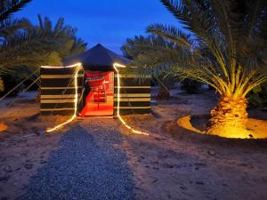 a tent with lights on the beach at night at Almazham camp resort in Al-ʿUla