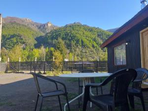 a table and chairs with mountains in the background at Peumayenlodge Cabaña moderna in Antuco