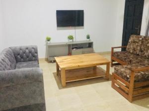 sala de estar con 2 sillas, mesa y TV en Hyven's Apartments, en Mtwapa