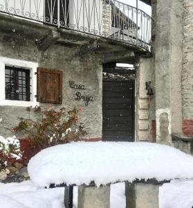 eine schneebedeckte Bank vor einem Gebäude in der Unterkunft Casa Bruja Tradizionale Rustico Ticinese in Mergoscia