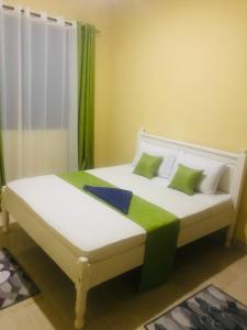 1 dormitorio con 1 cama con almohadas verdes y blancas en Hyven's Apartments en Mtwapa