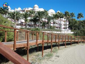 un puente de madera frente a un complejo con palmeras en Residencial Casablanca Casa Azahar, en Alcossebre