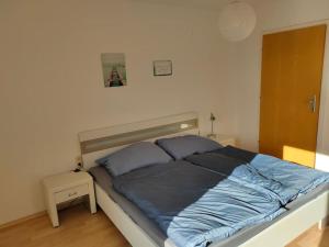 um quarto com uma cama com lençóis azuis em Ferienwohnung ländlich und in Seenähe em Schörfling