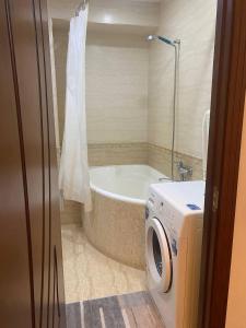 uma casa de banho com uma máquina de lavar roupa e uma banheira em Comfortable 2 rooms apt in Centre of Tashkent city em Tashkent