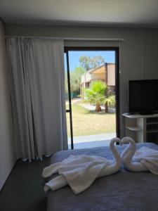 two swans sitting on a bed in front of a window at Terraverde Apartment in Ciudad Lujan de Cuyo