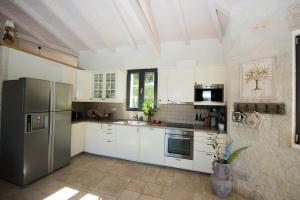uma cozinha com armários brancos e um frigorífico de aço inoxidável em Villa Sania em Kassiopi