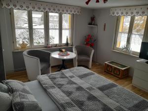 Schlafzimmer mit einem Bett, einem Tisch und Fenstern in der Unterkunft Haus Hubertus in Stolberg i. Harz