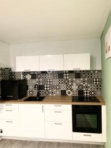 a kitchen with white cabinets and black and white tiles at Le Corbusier - Cosy & SPA in Firminy