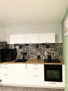 a kitchen with white cabinets and black and white tiles at Le Corbusier - Cosy & SPA - Appartement in Firminy +3 photos