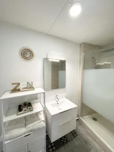 a white bathroom with a sink and a shower at Le Corbusier - Cosy & SPA in Firminy