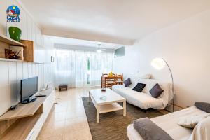 a living room with a white couch and a tv at Apartamentos Arcos II Casa Azahar in Alcossebre