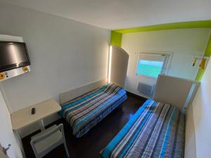カルカソンヌにあるHotel Class'Eco Carcassonneのベッド2台と窓が備わる小さな客室です。